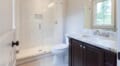 a small bathroom with dark wood cabinetry, white walls, and a shower stall